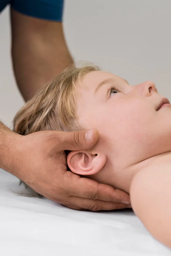 two hands gently hold the head of a child as he's laying down