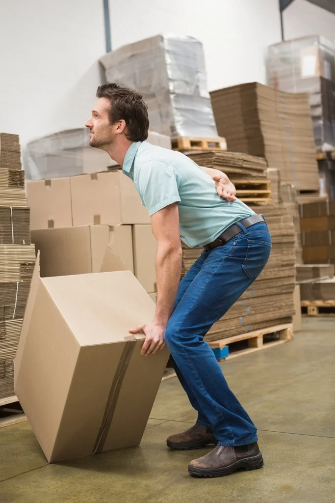 Man Holds Lower Back As He Lifts Boxes