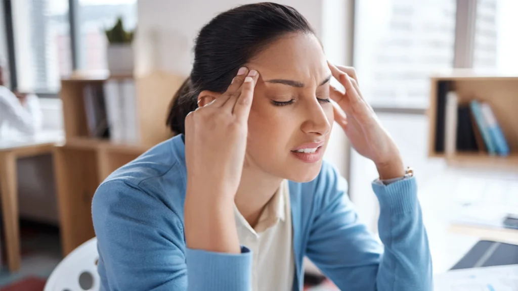 Woman Suffers From A Headache At Work